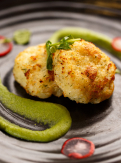fish cakes on a black plate with green garnish