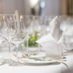 Close up of dinner table decoration with white linen and silverware