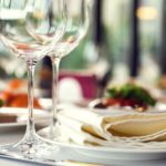 close up of table place settings with wine glasses in foreground