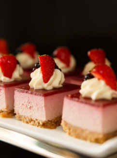 Close up of pink desserts with strawberry and cream on a plate