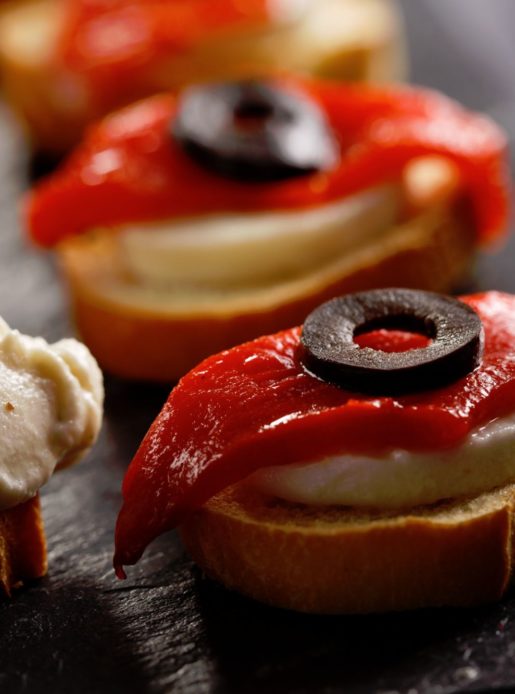 Canapes with red peppers and olives on a slate